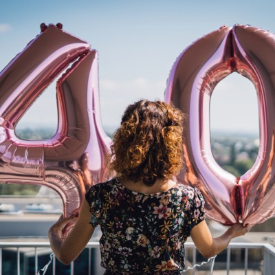 things to do before you turn 40. woman 40th birthday. woman holding "4" and "0" balloons on balcony