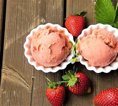 three containers of strawberry ice cream and loose strawberries