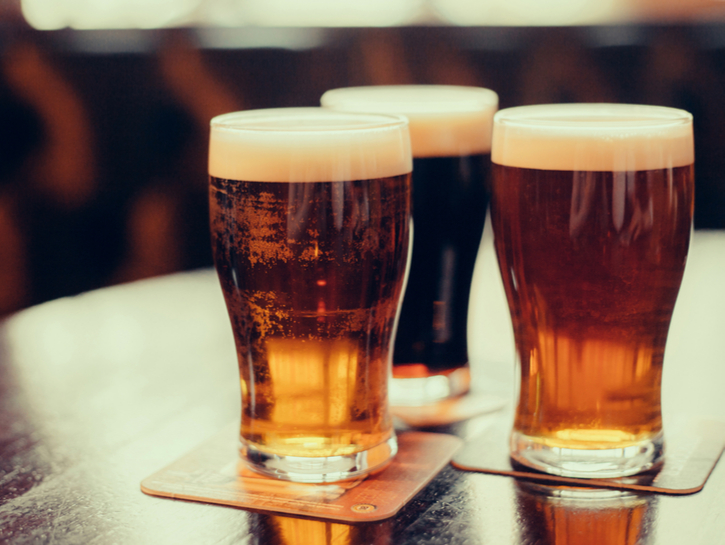 three glasses of beer sitting on a wooden table