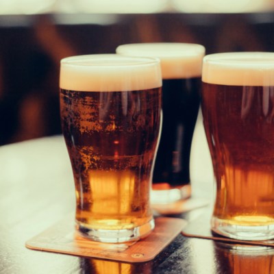 three glasses of beer sitting on a wooden table