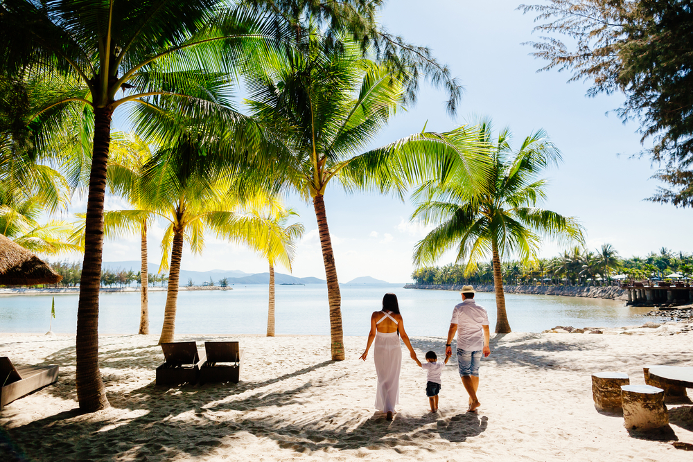 unidentified family vacation on luxury beach resort in tropics back view