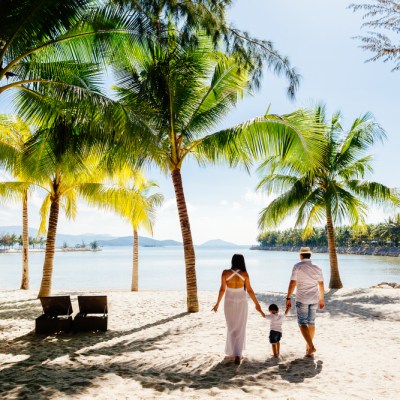 unidentified family vacation on luxury beach resort in tropics back view