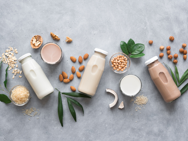 Variety of bottled plant-based milks next to ingredients