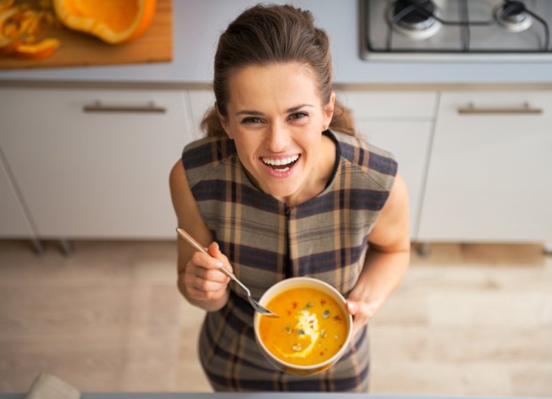 Vegetarian Slow Cooker Recipes Happy young woman eating pumpkin soup in kitchen