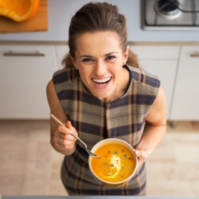Vegetarian Slow Cooker Recipes Happy young woman eating pumpkin soup in kitchen