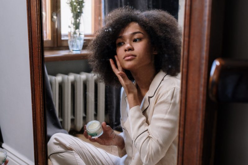 woman applying acne cream in front of mirror