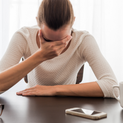 Woman at desk holding her head in her hand