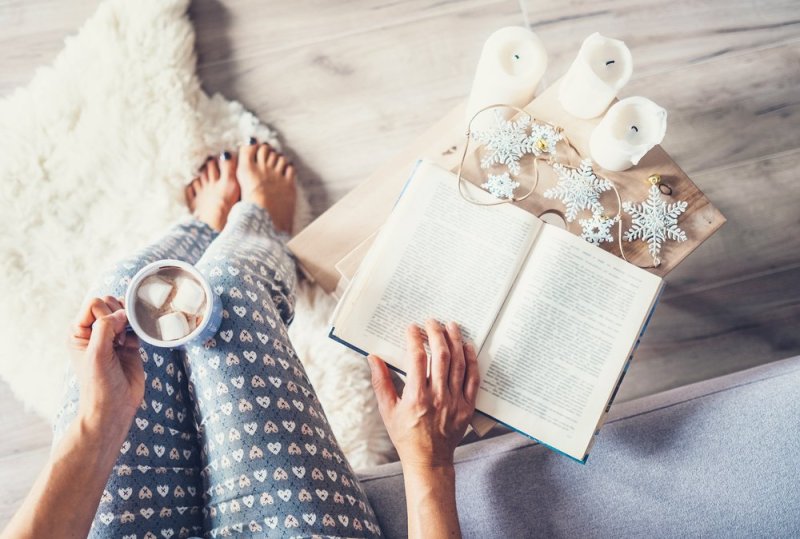 Woman drinks hot chocolate and reads a book in cozy home atmosphere