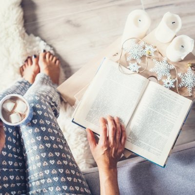Woman drinks hot chocolate and reads a book in cozy home atmosphere