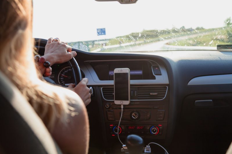 woman driving and listening to an audio book on her phone