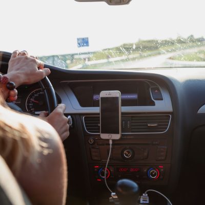 woman driving and listening to an audio book on her phone