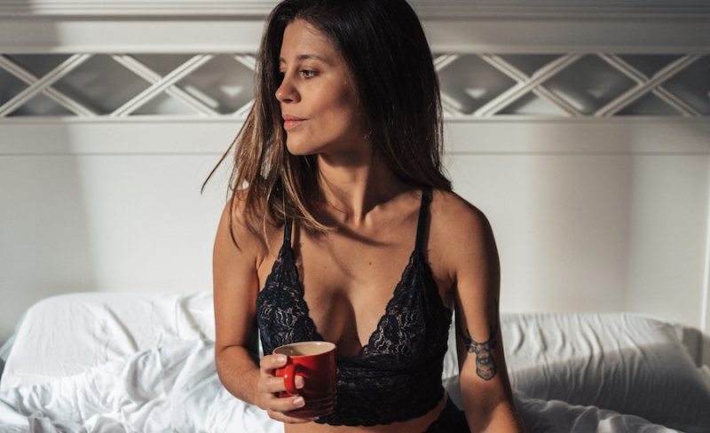 woman in bralette in bed with coffee