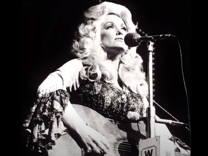 Young Dolly Parton singing and playing guitar