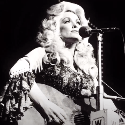 Young Dolly Parton singing and playing guitar