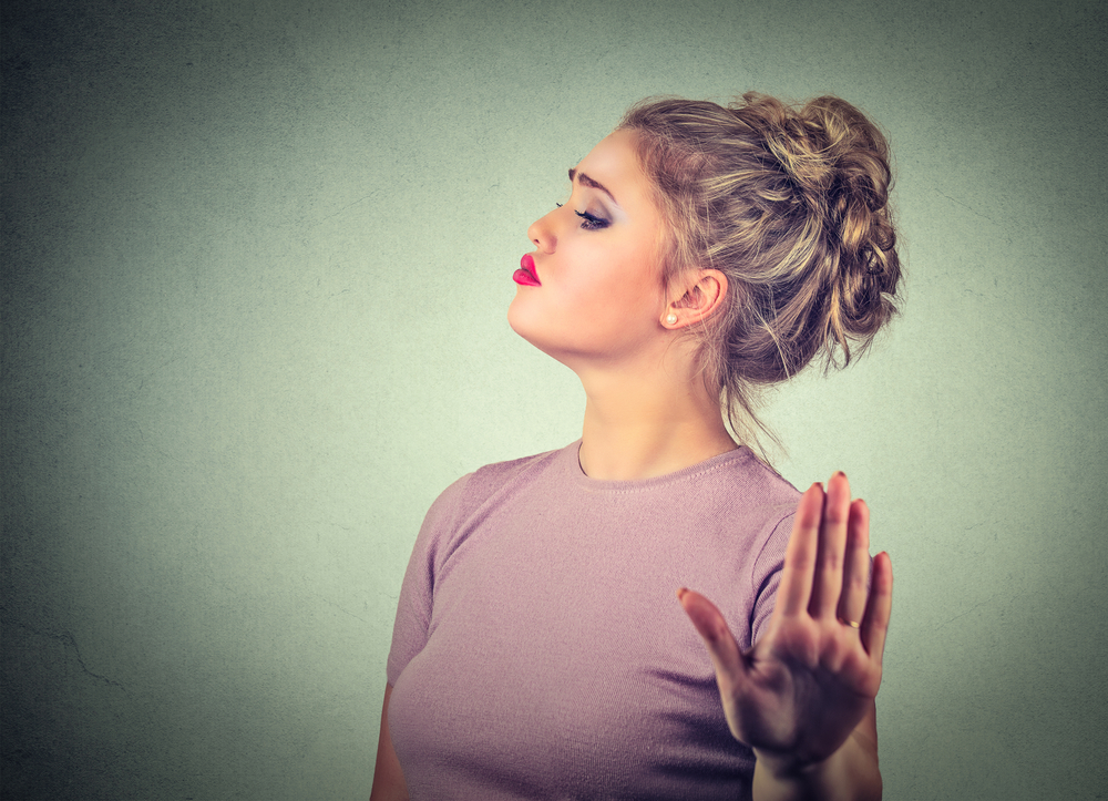 Snobby young annoyed angry woman with bad attitude giving talk to hand gesture with palm outward isolated grey wall background. Negative human emotion face expression feeling body language