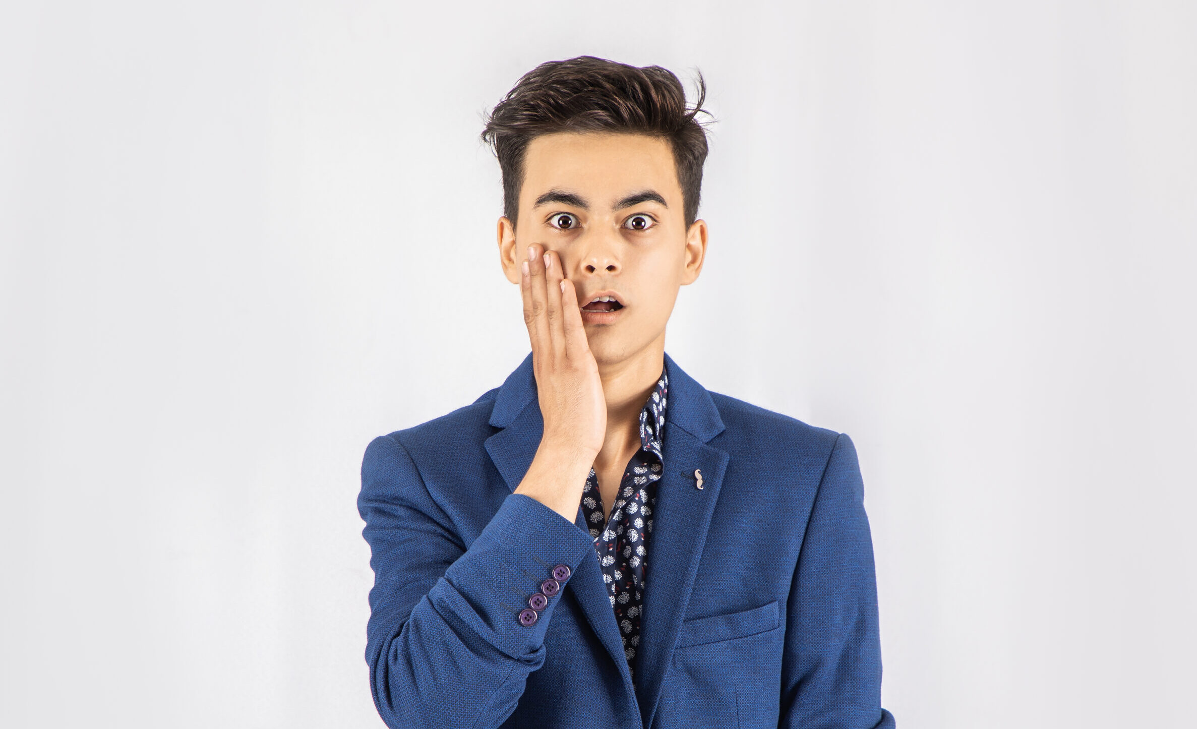 Photo of shocked man in blue blazer standing in front of white background