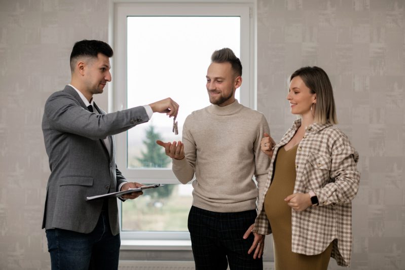A real estate agent handing the key to the new homeowners
