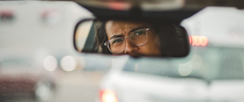 Man looking back through rear view mirror