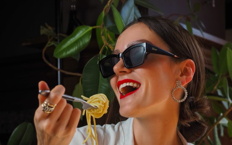 Smiling woman eating pasta in restaurant