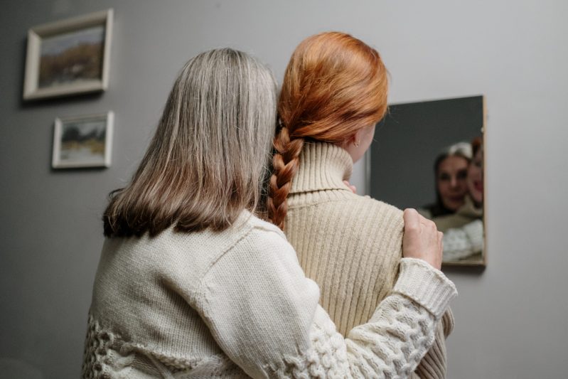 A mother and daughter looking at the mirror