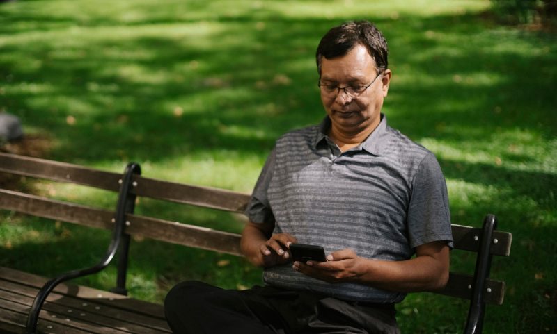 Man surfing net sitting on bench