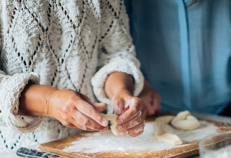 Person holding white dough on brown wooden table