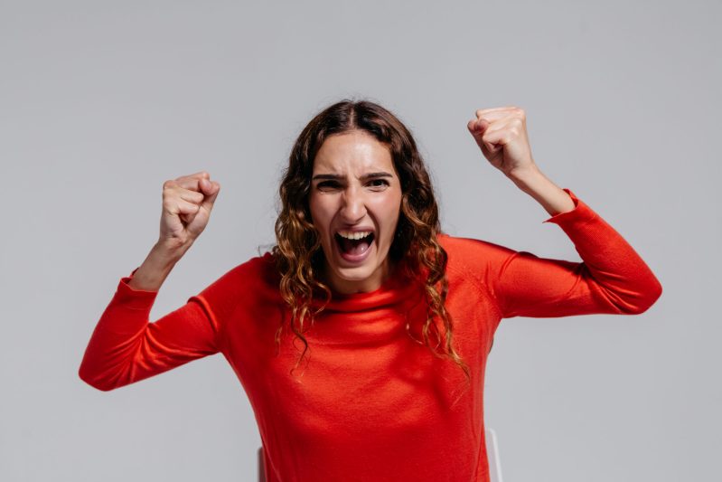 Photo of an angry woman in red long sleeve shirt