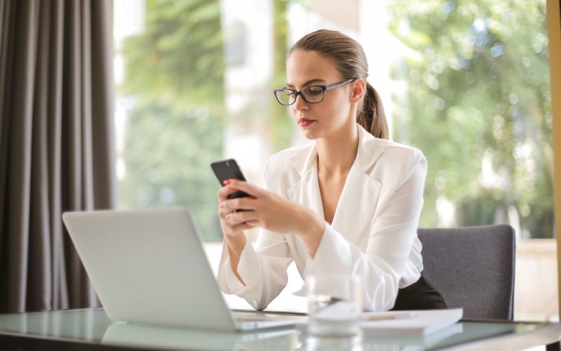Serious businesswoman using smartphone in workplace