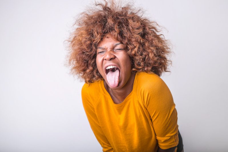 Grimacing ethnic woman with tongue sticking out in studio