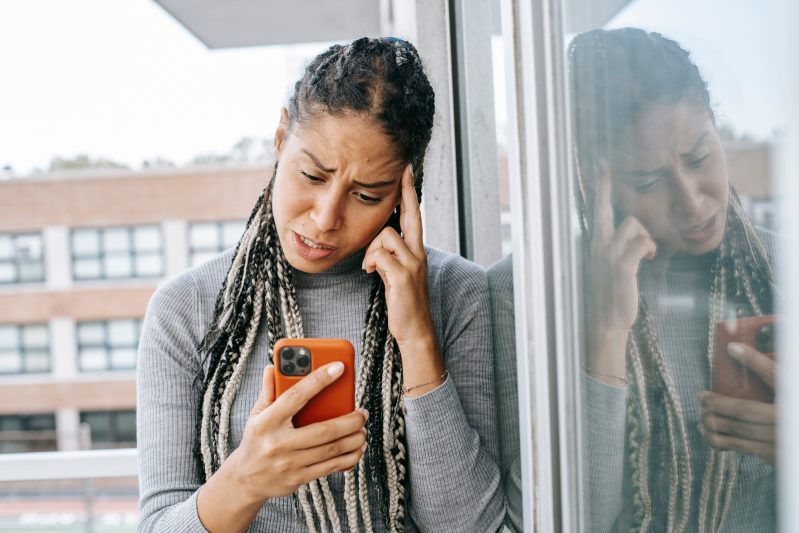 Tired black woman browsing mobile phone