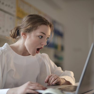 Woman in white long sleeve shirt using silver laptop computer