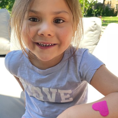 Smiling child with heart shaped hydrogel patch on wrist.