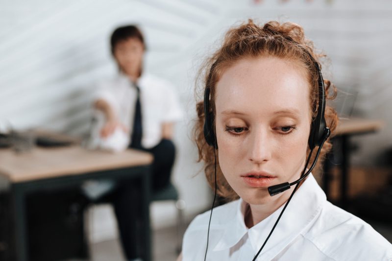 Woman in white top wearing a black headset