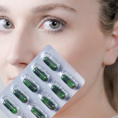 woman holding invity supplement capsules in front of her face