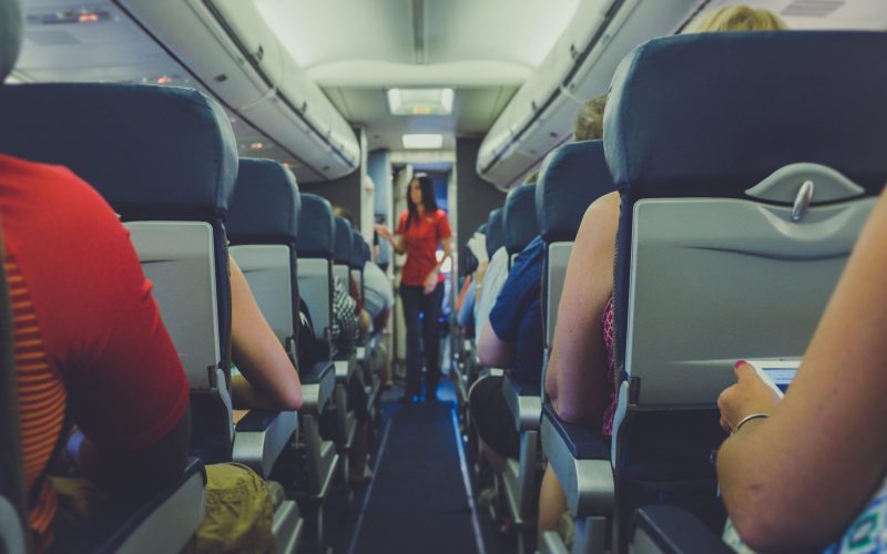 flight attendant standing between passenger seat