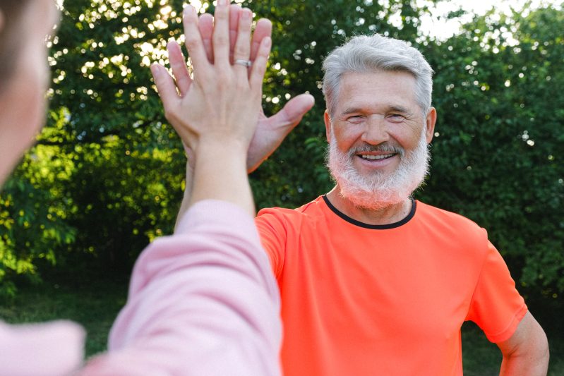Smiling elderly man giving high five
