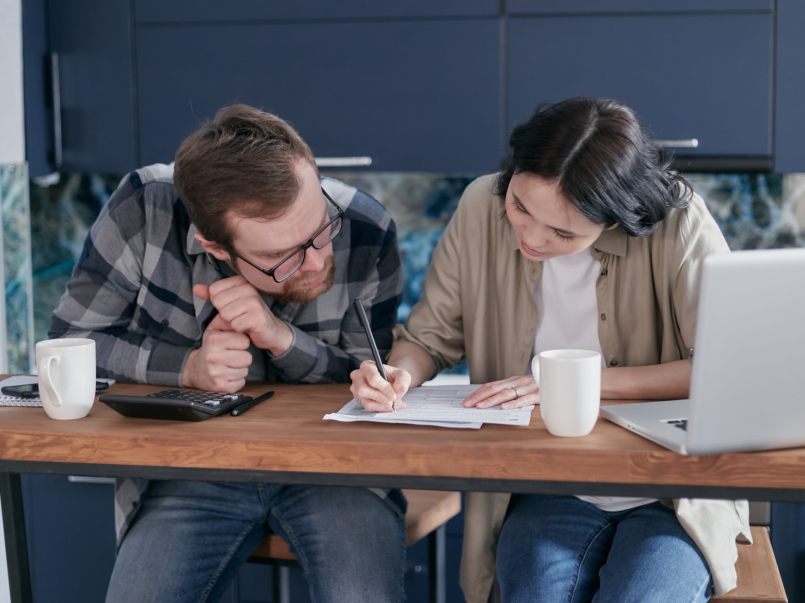 Woman in brown shirt writing on paper beside a man