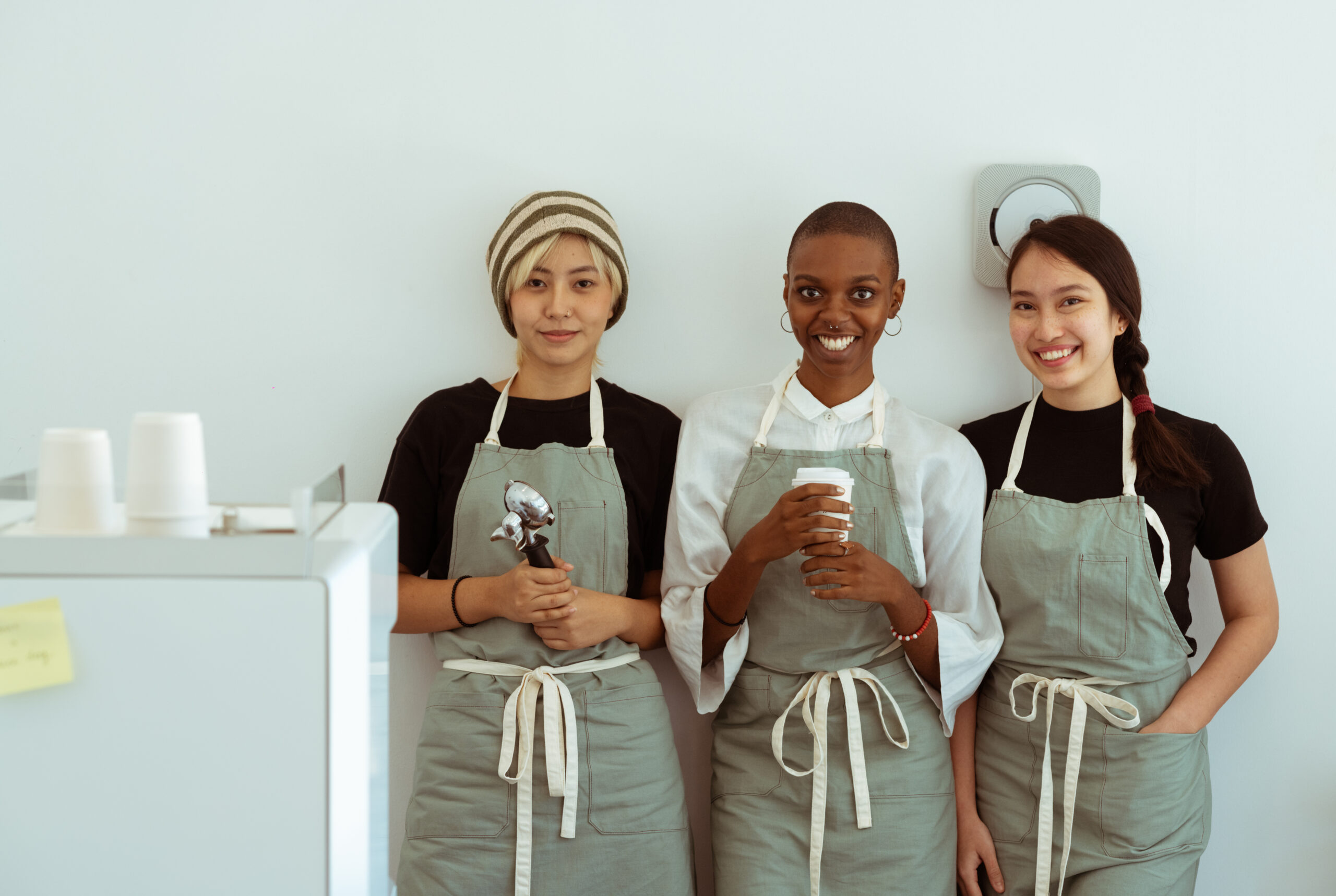 Delighted baristas with portafilter and paper cup