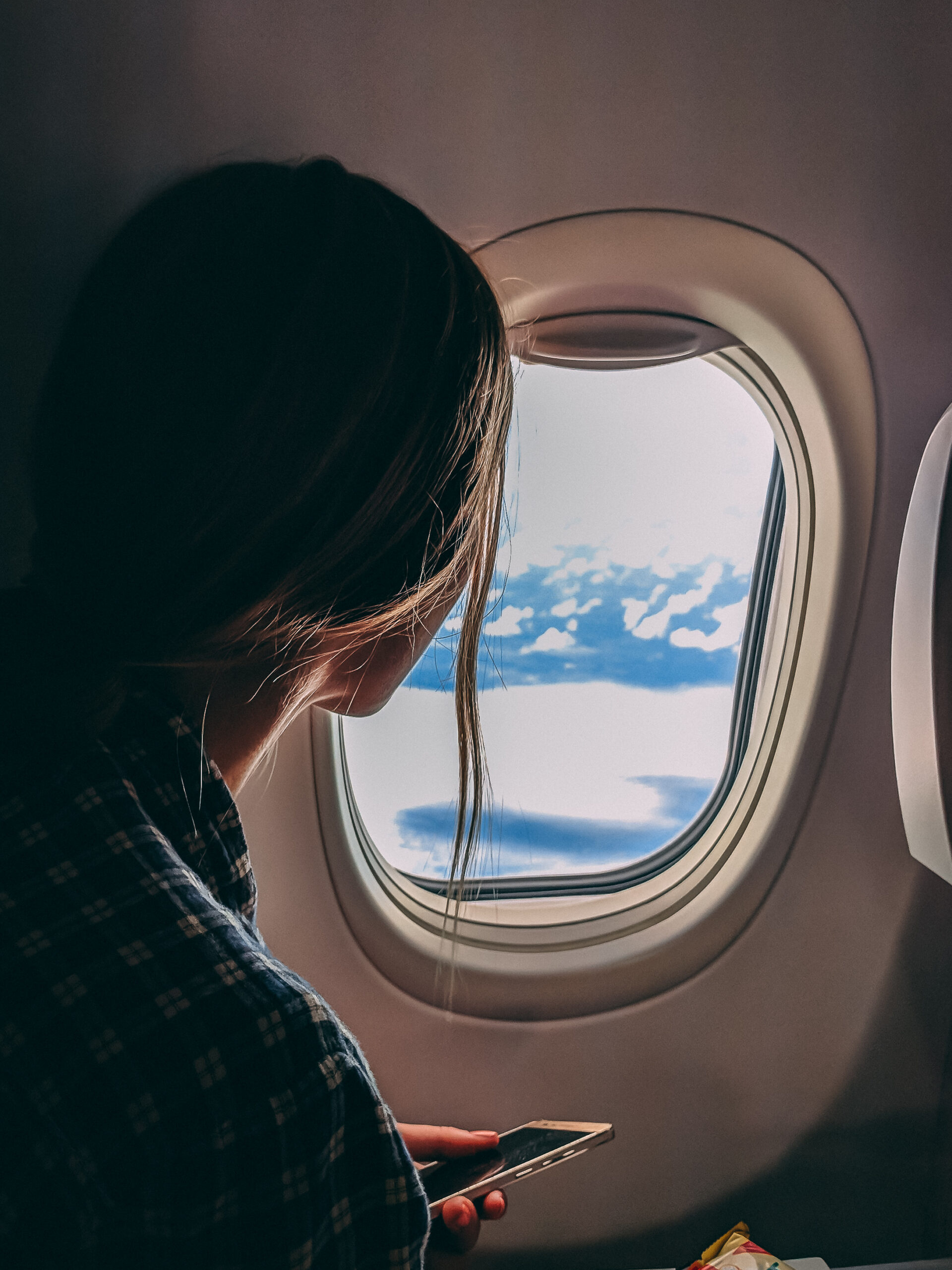 Person holding smartphone riding airplane