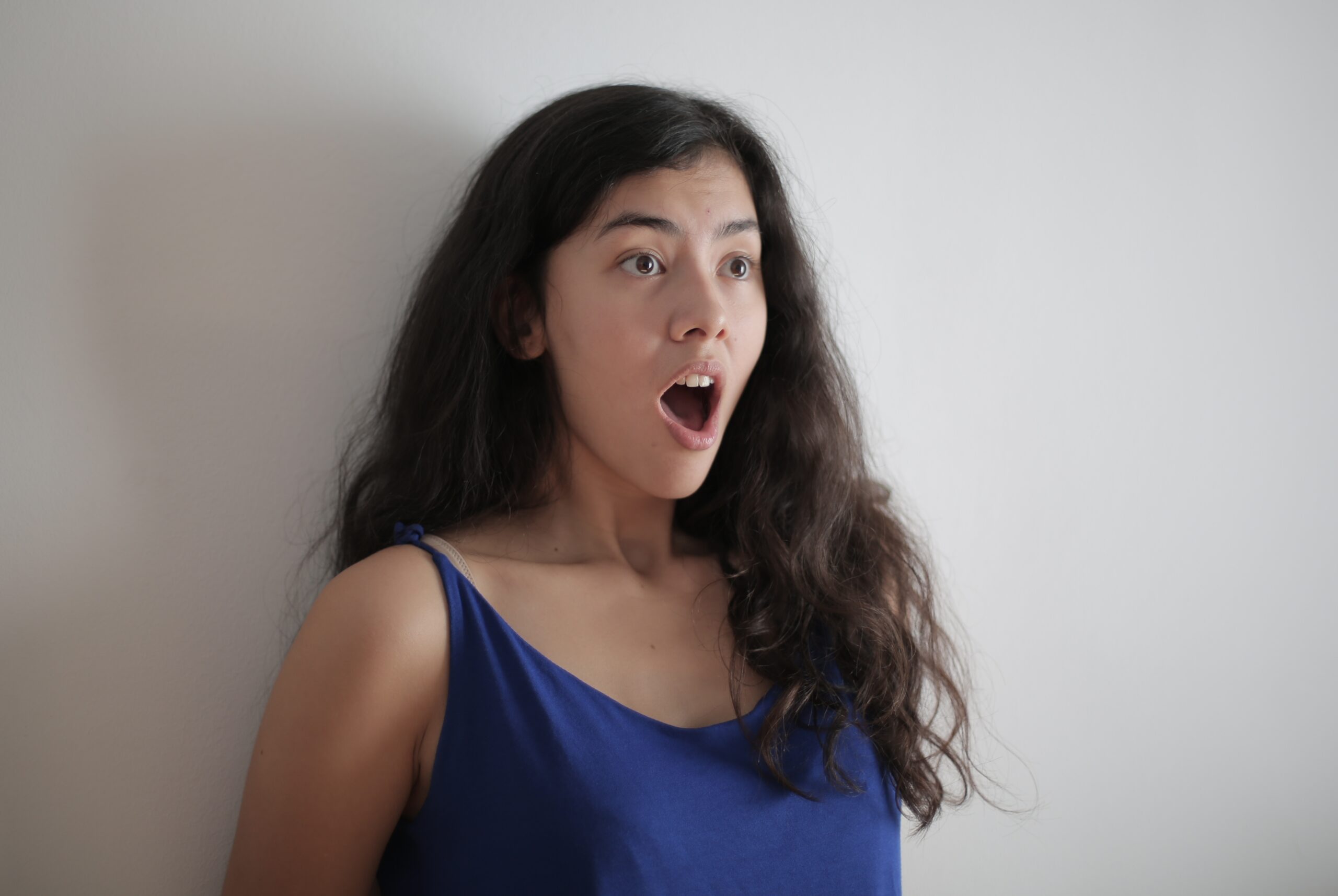 Woman in blue tank top standing next to wall