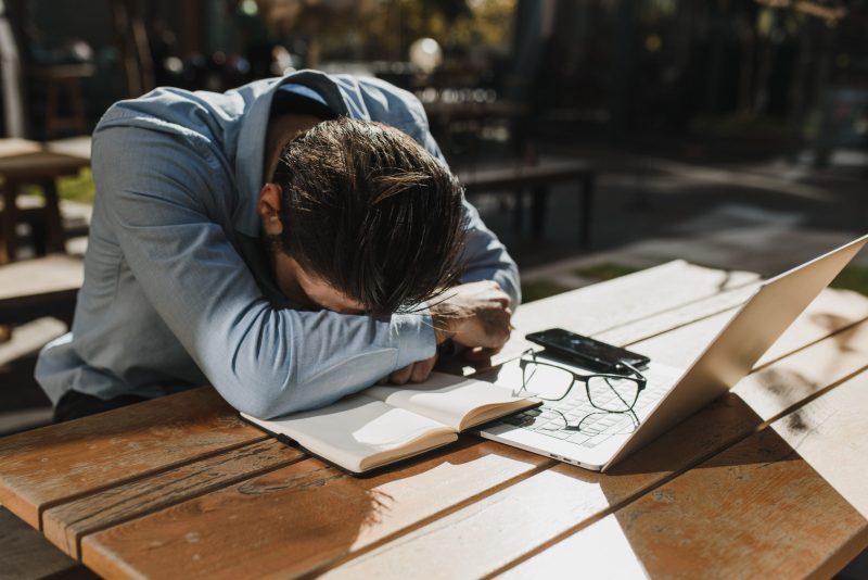 A tired man resting on a wooden table